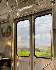 two people sitting on a train looking out the windows at green grass and blue sky