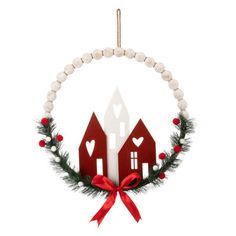 a christmas ornament hanging on a white wall with red and white houses in the background