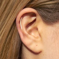 a woman's ear is shown with a thin piece of gold in the middle