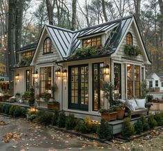 a small house with lots of windows and plants on the roof