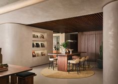 a kitchen with a center island surrounded by wooden chairs and counter tops, along with shelves on the wall