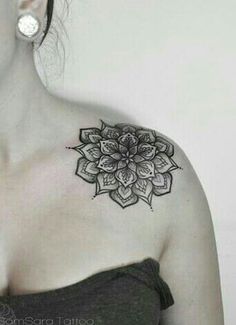 a woman with a tattoo on her shoulder has a black and white flower in the center