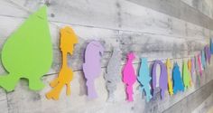 colorful paper cutouts are hanging on the side of a wooden wall in an art gallery