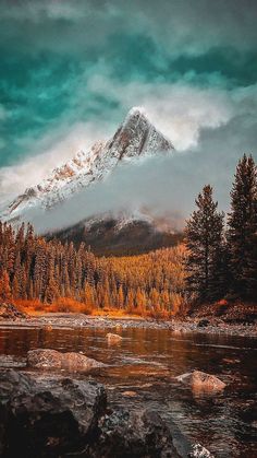 a mountain covered in snow sitting next to a river