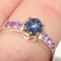 This delicate ring is a size 6 1/2, Sterling Silver, Blue Star Sapphire, with 6 bright purple, faceted Amethysts on the band, 3 on each side of the center stone. This charming little ring would make a treasured gift, a promise ring, or even an engagement ring. Star Sapphire Ring Purple, Blue Star Sapphire Ring, Star Sapphire Ring, Blue Star Sapphire, Star Sapphire, Silver Work, Bright Purple, Delicate Rings, Welo Opal