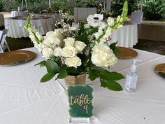 there is a vase with white flowers on the table at this wedding reception and place card holders