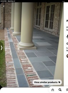 an outdoor patio with columns and grass in the foreground, surrounded by brick walkways