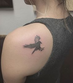 a woman's shoulder with a bird tattoo on the left side of her arm