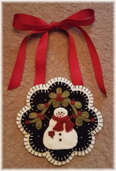 a snowman ornament hanging from a red ribbon on top of a carpet