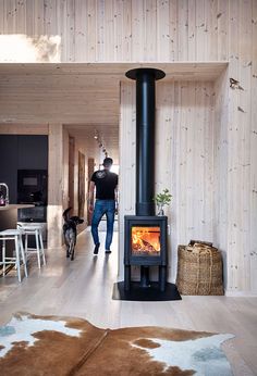 a man walking through a living room next to a fire place in the middle of a kitchen