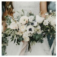 a bride holding a bouquet of white and pink flowers with greenery in her hands