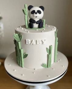 a panda bear sitting on top of a white cake with bamboo trees in the background