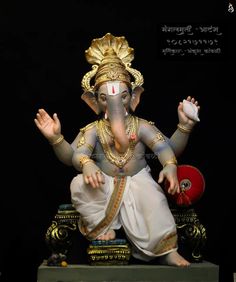 an elephant statue sitting on top of a wooden table next to a red ball and black background