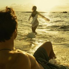 two people are in the water at sunset