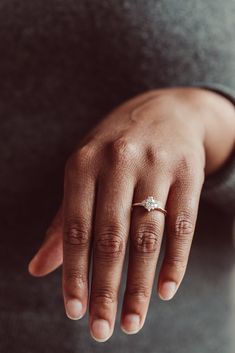 a close up of a person's hand with a diamond ring on their finger