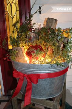 an old metal bucket filled with plants and candles on top of a wooden stand in front of a door