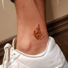 a woman's foot with a small fire tattoo on her left side ribcage