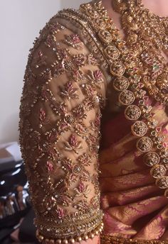 the back of a woman's sari with gold and pink beads on it