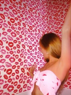 a woman in a pink bathing suit standing next to a wall with red lipstick on it