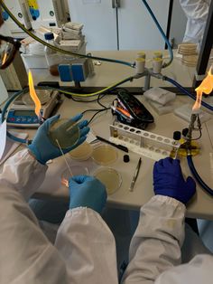 two people in white lab coats and gloves working on an experiment with yellow flames coming out of them