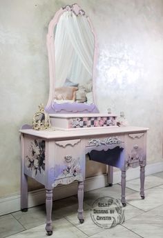 a pink vanity with flowers painted on the side and a white canopy over it's top