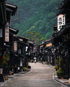 an empty street with mountains in the backgrouds and trees on both sides