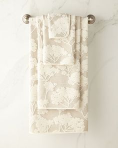 two towels hanging on a towel rack in front of a marble wall with white flowers