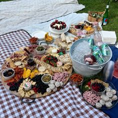 an outdoor picnic with food and drinks on the table, including cheeses, crackers, strawberries