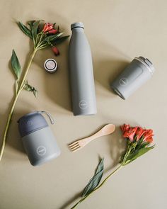 flowers and utensils on a table next to thermos, spoons and cups