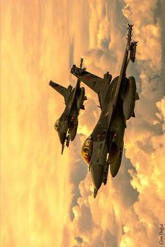 two fighter jets flying in the sky with clouds behind them and one is upside down