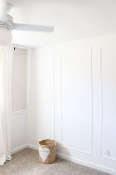 an empty room with a ceiling fan and a basket on the floor in front of it