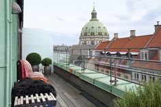 a balcony with a bench, potted plants and buildings in the background