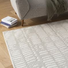 a living room area with a couch, rug and book on the floor in front of it