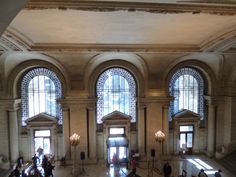 the inside of a building with many windows and people walking around it in front of them