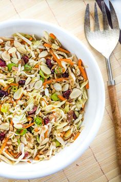 a white bowl filled with shredded carrots, cranberries, nuts and seeds