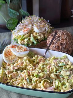 a bowl filled with pasta and an egg on top of it next to another bowl full of bread