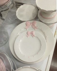 white dishes with pink bows on them are sitting on a table