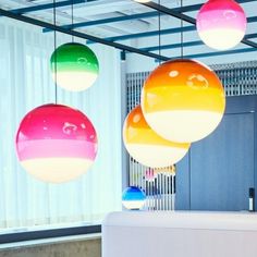 three multicolored balls hanging from the ceiling in an office lobby with white walls