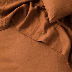 an unmade bed with brown sheets and pillows