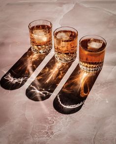 three glasses with ice in them sitting on a table