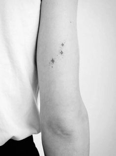 a woman's arm with small stars on the back of her left arm, in black and white