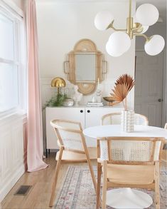 a dining room table with chairs and a mirror on the wall in front of it