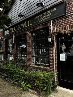 the black veil storefront is shown in front of some bushes and plants outside it