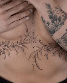 a woman with tattoos on her chest holding her hands to her chest