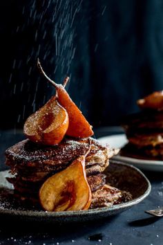 a stack of pancakes covered in powdered sugar and sliced apples