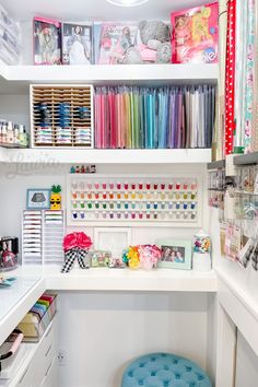 a sewing room with lots of craft supplies on the shelves and in front of it is a blue stool