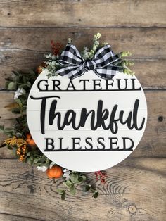 a white sign that says grateful, thanksgiving, and is hanging on a wooden wall