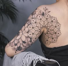 a woman with a tattoo on her arm and shoulder is sitting in front of a plant