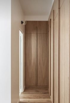 an empty hallway with wooden closets and white walls