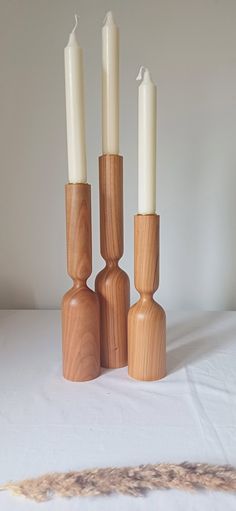 three wooden candlesticks with one candle in the middle and two on each side